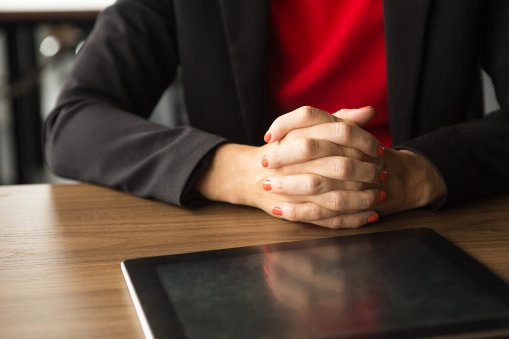 clasped hands of businesswoman and digital tablet