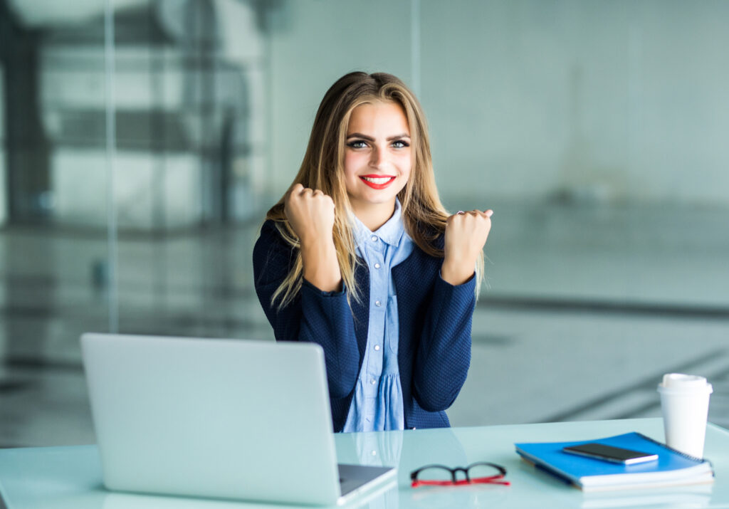 excited businesswoman winning after achievement sitting in a desktop at office
